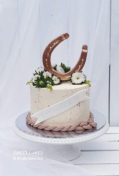 there is a cake that has a horseshoe on top and flowers in the middle, along with a ribbon around it