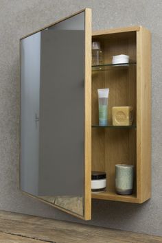 a wooden cabinet with glass doors and shelves on the wall next to a wood floor