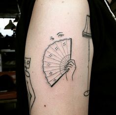 a person with a tattoo on their arm holding a fan