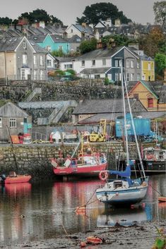 there are many boats that are docked in the water near some houses and buildings on the shore