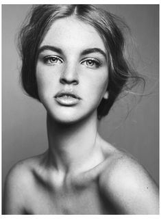 a black and white photo of a woman with freckles on her chest, looking at the camera