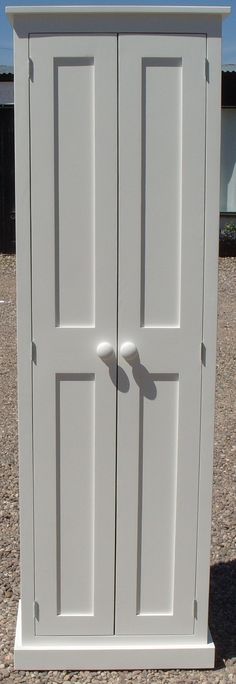 a white cabinet sitting on top of a gravel field