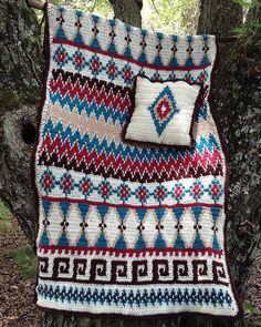 a crocheted blanket and two pillows on a tree