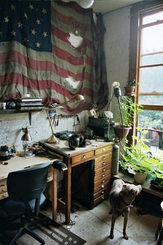 an american flag hanging in the corner of a room next to a desk and chair