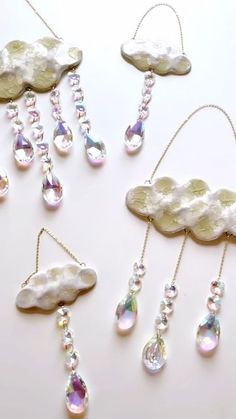 several different types of necklaces on a white surface with clouds and water drops hanging from them