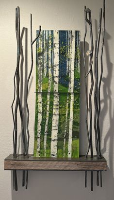 an art piece is displayed on a shelf in front of a white wall and some branches