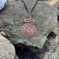 Adorn your neck with the Serpentine Spiral Necklace, a mesmerizing blend of elegance and artistry, inspired by the graceful serenity of nature. -Pendant width: 2.5 Inches -Pendant height: 1.5 Inches -Materials: Copper Available only with suede cord/lobster claw closure. Bohemian Spiral Necklace As A Gift, Bohemian Spiral Necklace As Gift, Bohemian Spiral Necklace For Gift, Bohemian Swirl Jewelry As A Gift, Bohemian Swirl Jewelry For Gifts, Handmade Swirl Necklace For Gift, Handmade Spiral Copper Necklace, Queens Jewels, Spiral Necklace