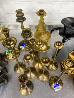 an assortment of brass candlesticks and candle holders