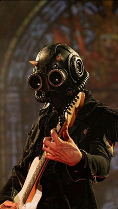 a man in a gas mask playing an electric guitar