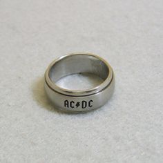 a silver ring with the word ac dc on it sitting on a white table top