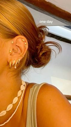 a close up of a person with ear piercings on their ears and wearing gold jewelry