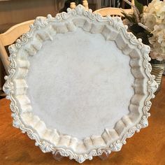 a white plate sitting on top of a wooden table next to vases with flowers