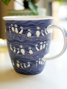 a blue and white coffee cup with penguins on it