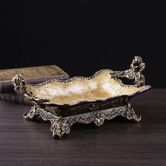 an ornately decorated metal bowl on top of a wooden table next to a book