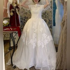 a woman in a white dress standing next to some dresses