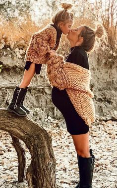 two women kissing each other while standing on a tree branch