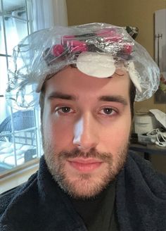 a man with a plastic bag on his head and flowers in the hair is looking at the camera