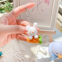 a hand holding a tiny keychain with a small animal on it