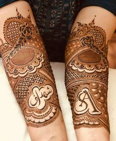 two hands with henna tattoos on them, one is showing the letter a and the other