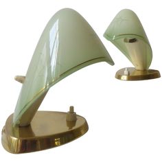 two green glass lamps sitting on top of brass bases, one is turned upside down