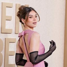 a woman in a pink dress and black gloves on the red carpet at an event