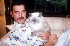 a man sitting on a couch holding a cat