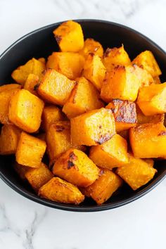 a black bowl filled with cooked potatoes on top of a white counter