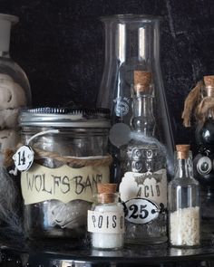 various bottles and jars are sitting on a table with halloween decorations around them, including pumpkins