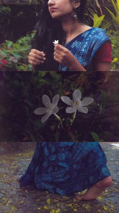 a woman sitting on the ground with flowers in her hand and looking up at something