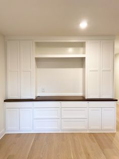 an empty room with white cabinets and wood floors