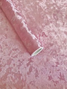 a roll of pink crushed velvet fabric on top of a tablecloth covered in flowers