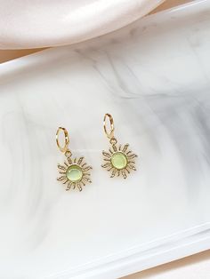 A Beautiful and cute pair of sunflower earrings that are a lovely lime light green opal cats eye effect to give them that shine, on a lever back stainless steel gold coloured hook, very stylish and pretty and great for a summer vibe. I think these earrings are very cute and stylish, they give off a lot of shine in the light so they would look really pretty out in the sun with a summers dress. These earrings are nice and light in weight so they will not feel too much of a burden wearing them for a long time. MATERIALS: The earring leverbacks are made from stainless steel which is hypo-allergenic, which means decreased tendency to cause an allergic reaction. HOW TO CARE FOR YOUR JEWELLERY To keep jewellery looking fresh and extend its lifespan it is recommended to: - Remove jewellery before Dainty Green Summer Jewelry, Cute Yellow Jewelry With Matching Earrings, Green Hypoallergenic Earrings For Summer, Green Hoop Earrings As Summer Gift, Trendy Lime Green Jewelry For Gift, Summer Green Hypoallergenic Earrings, Green Hoop Earrings For Gifts, Trendy Lime Green Jewelry As A Gift, Green Hoop Earrings For Summer