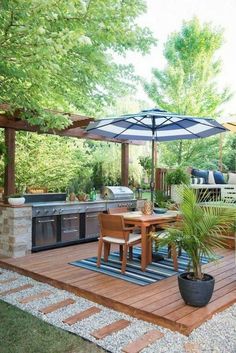 an outdoor kitchen and dining area is shown in this backyard setting with wooden decking