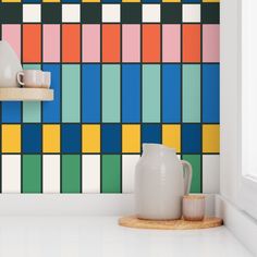 a white vase sitting on top of a counter in front of a colorful tiled wall