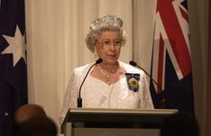 an older woman wearing a tiara standing at a podium