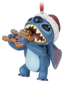 a christmas ornament with a blue monster holding a ginger in it's mouth