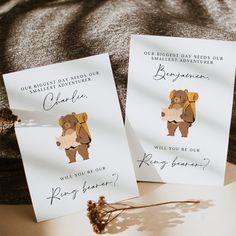 two greeting cards with bears on them sitting on a bed next to a plant and pillow