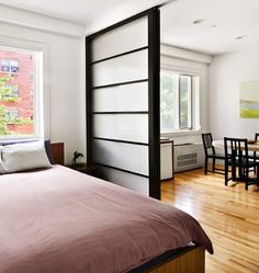 a bed sitting next to a window in a bedroom on top of a hard wood floor