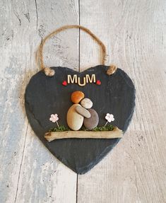 a heart shaped slate hanging on a wooden wall with the word mum painted on it