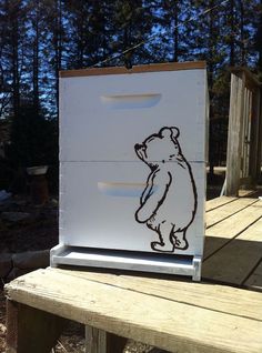 a drawing of a bear on the side of a white box sitting on top of a wooden bench