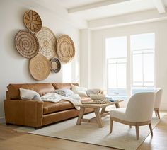 a living room filled with furniture next to a large window covered in wicker baskets