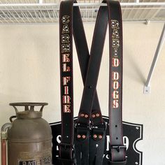 a pair of black leather suspenders sitting on top of a shelf next to a metal pot