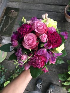 a bouquet of flowers sitting on top of a wooden table next to someone's feet