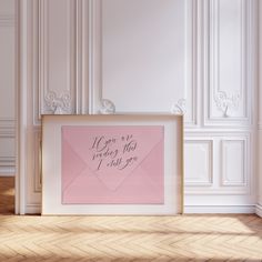 a pink envelope sitting on top of a wooden floor next to a framed sign that says, if you are never that i will you