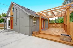 a house with a wooden deck and pergolated area next to the front door