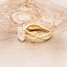 a gold ring with an oval cut diamond on top and vine design around the band