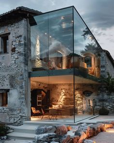 a glass house with stone walls and steps leading up to it