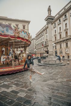 a woman is dancing in front of a merry - go - round on a rainy day