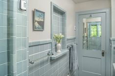 a bathroom with blue tile walls and white fixtures on the wall, along with a large mirror over the bathtub