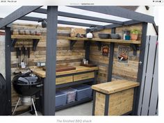 an outdoor kitchen made out of pallets and wooden planks is shown in this backyard